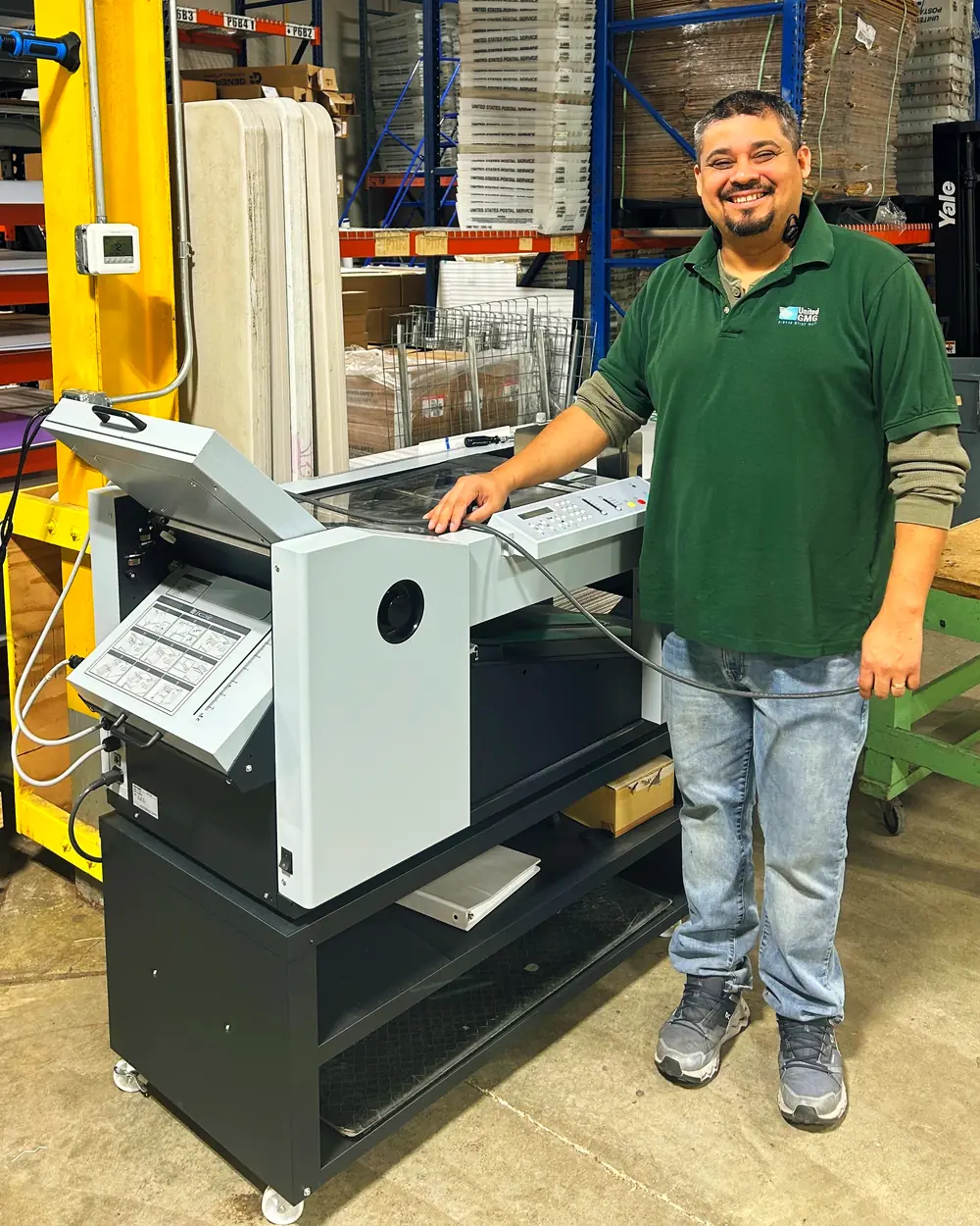 The operator at the paper folder in the plant, with the folded sheets coming off the machine