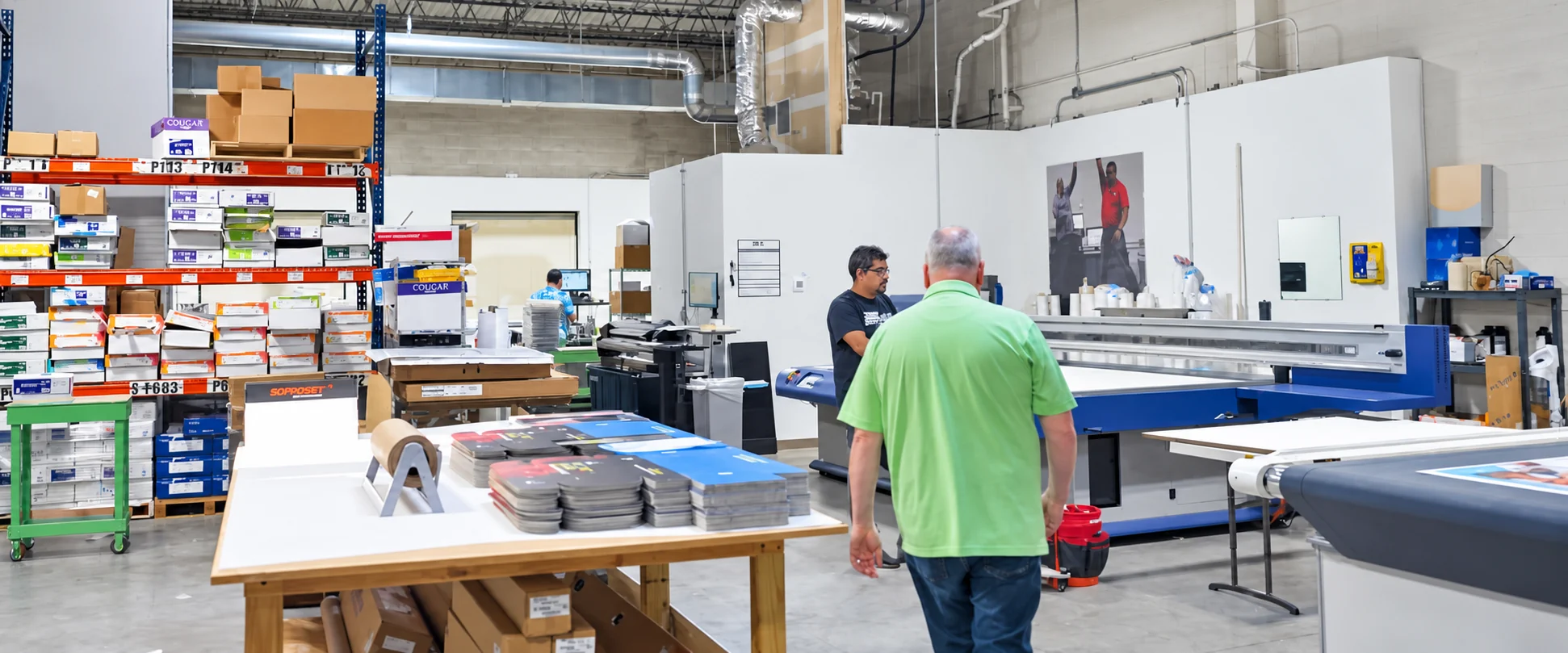 United GMG production staff working beside stacks of printed sheets in the pressroom